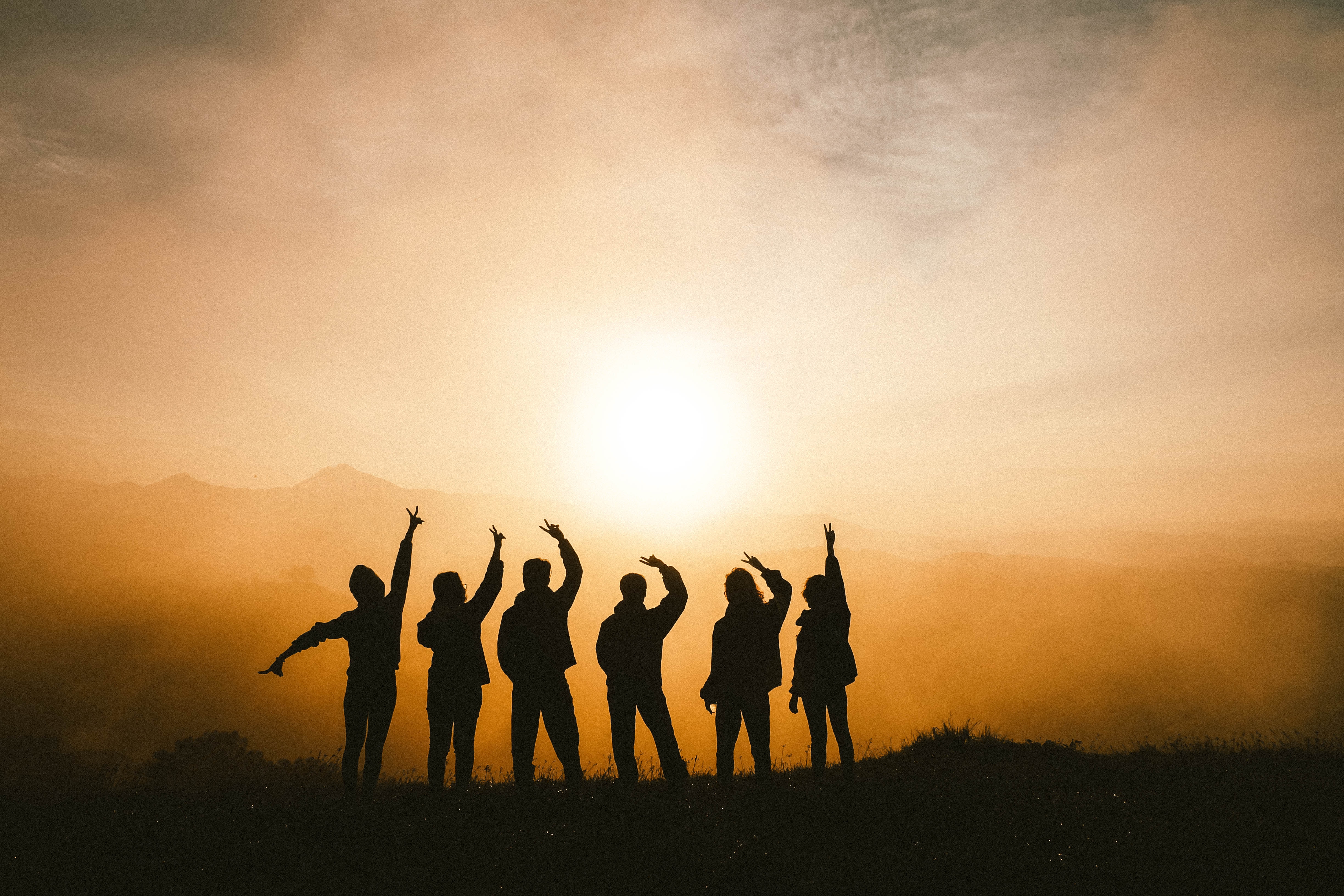 A group of people celebrating with a sunset backdrop.