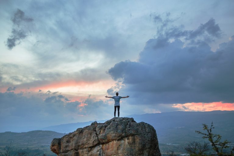 Person atop a mountain at sunset.